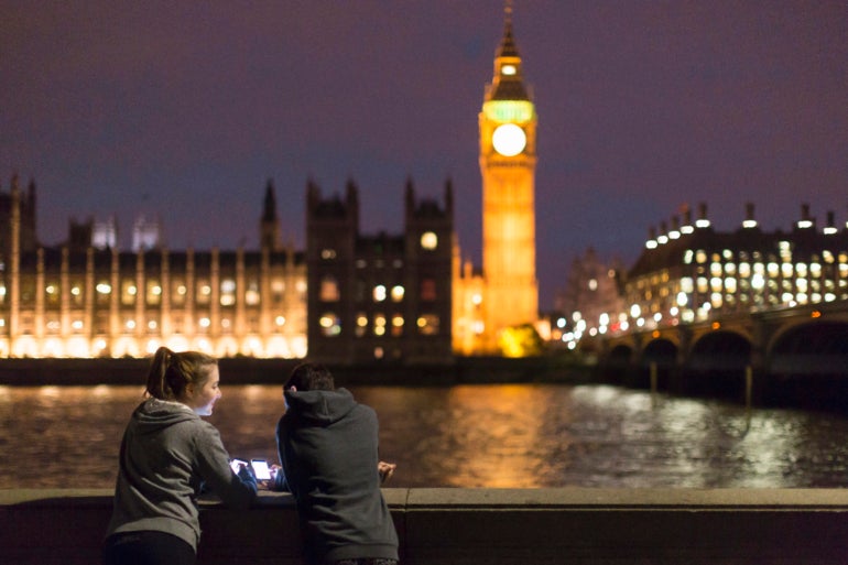 Rear View of Young Women Using Smartphone Opposite Palace of Westminster, London, Uk